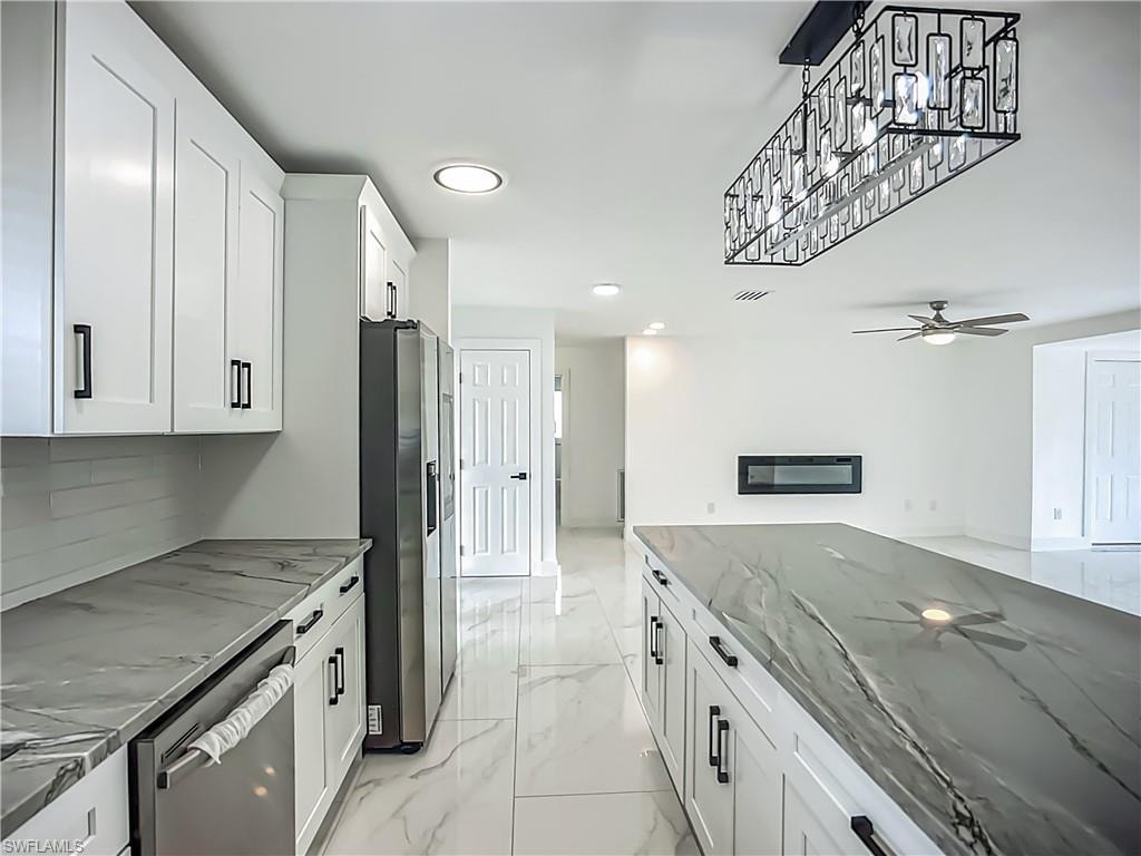 White shaker cabinetry with black hardware, stone-finish countertops, stainless steel appliances, ceramic tile flooring, and a linear electric fireplace