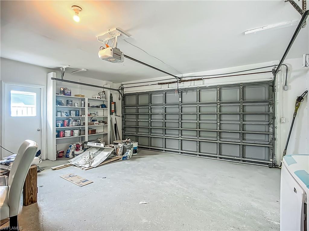 Integrated garage with a roll-up door, built-in shelving, and a side-entry door