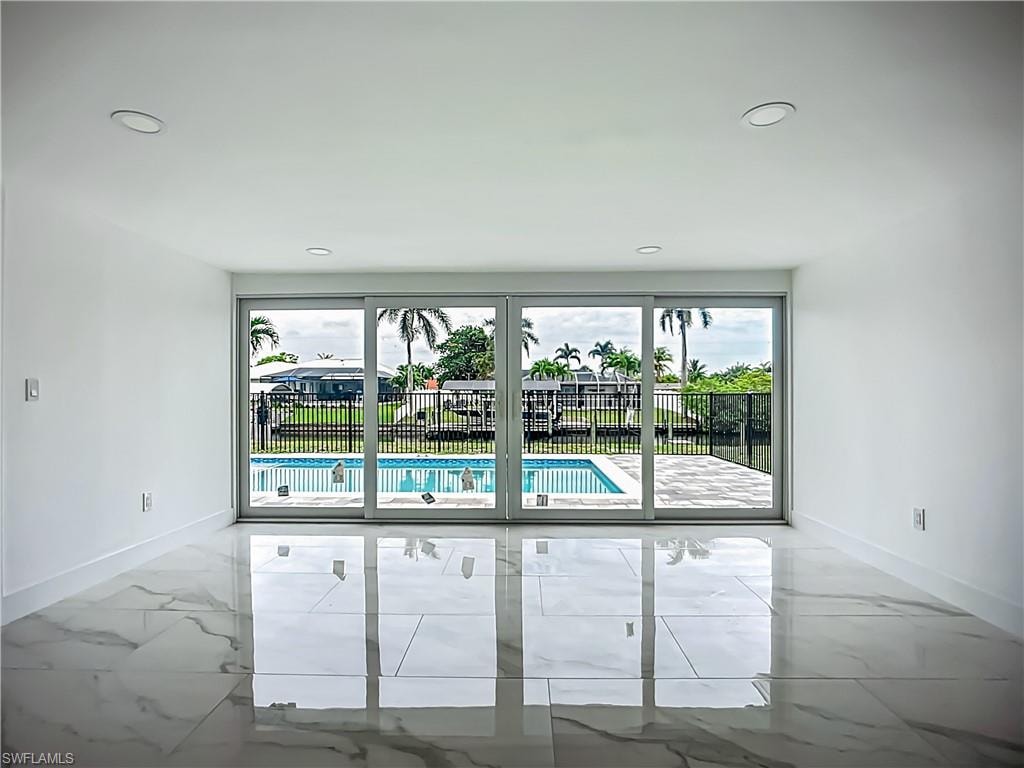 Polished tile flooring, recessed ceiling lighting, and sliding glass doors opening to a private pool and fenced outdoor area