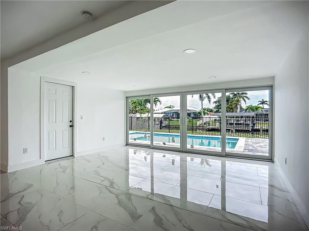 Polished tile flooring, recessed lighting, and sliding glass doors opening to an outdoor swimming pool