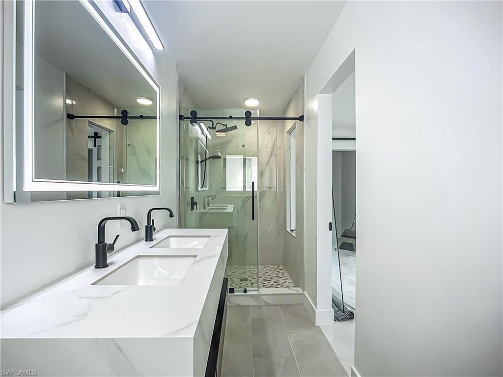 Dual vanity with integrated sinks, matte black fixtures, and a lighted mirror