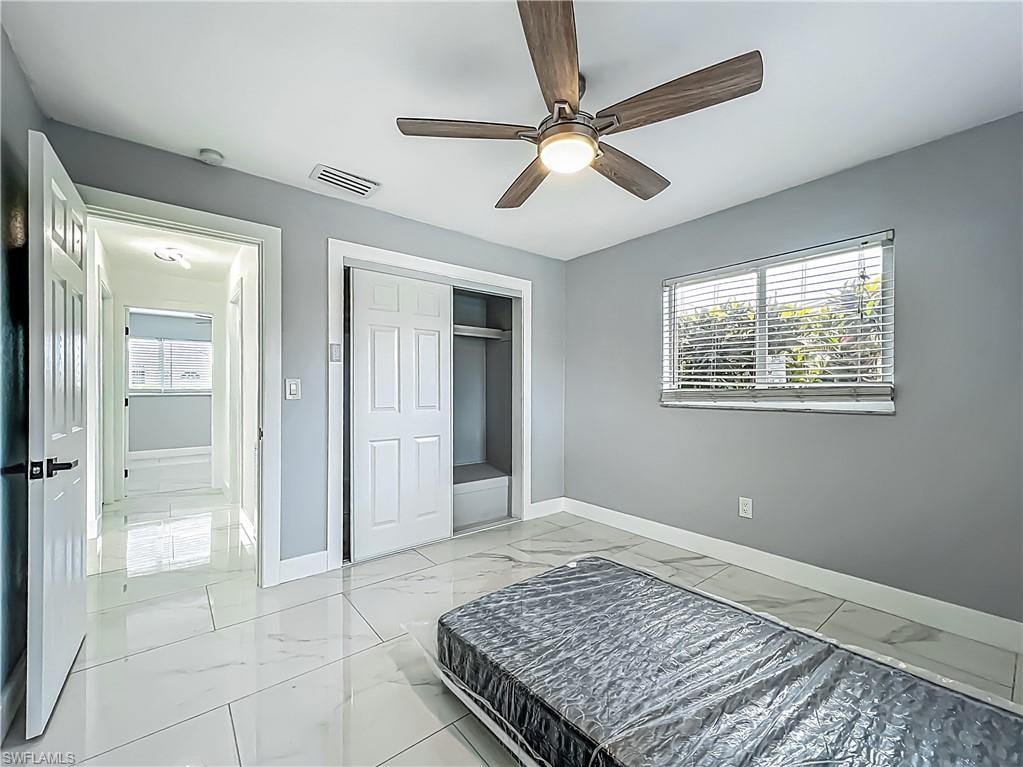White tile flooring, ceiling fan with integrated lighting, window with blinds, bi-fold closet doors, and recessed lighting in the hallway