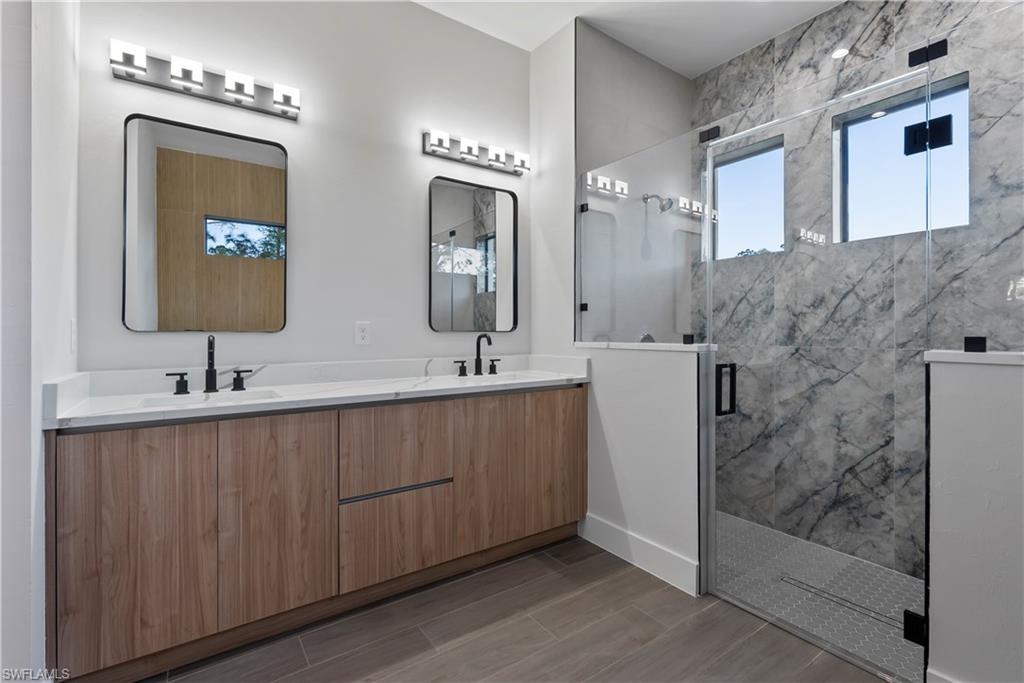 Double vanity with wood-finish cabinetry, white countertops, and matte black fixtures
