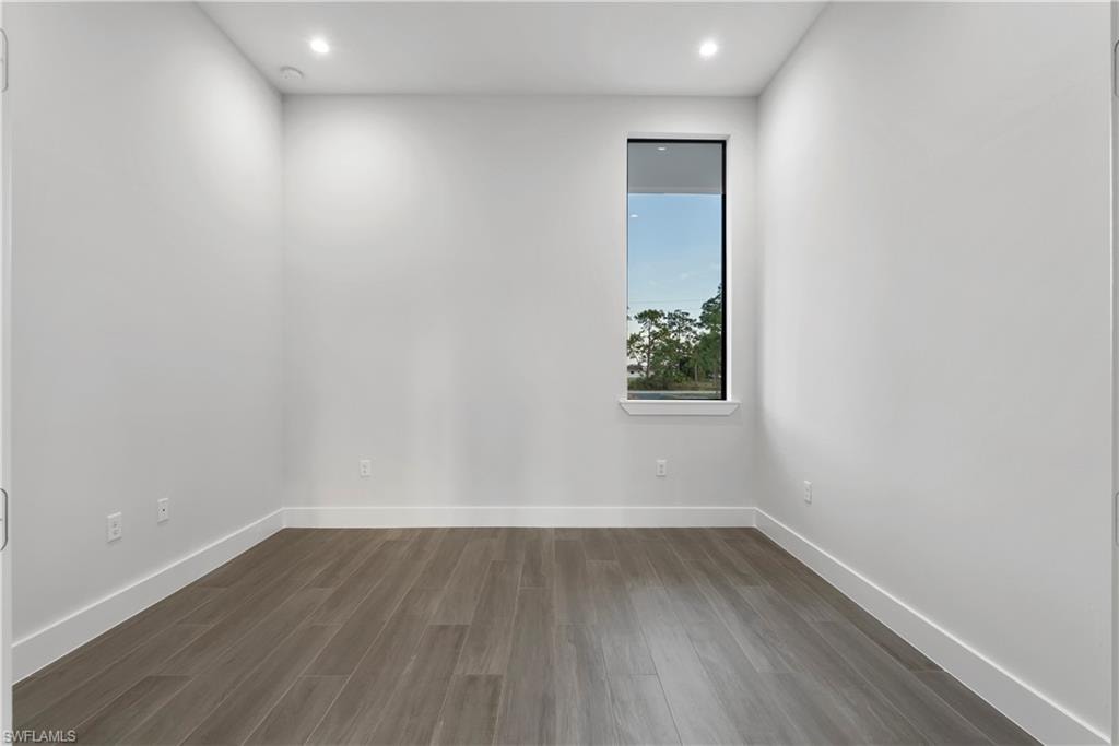 Wood-finish flooring, recessed lighting, and a vertical window
