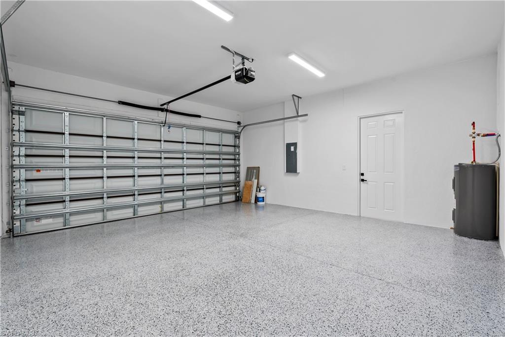 Spacious garage with an epoxy-coated concrete floor, an overhead garage door, and a paneled interior door