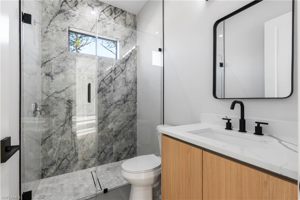 Modern bathroom featuring a walk-in shower with stone-finish tile, glass enclosure, and hexagonal tile flooring