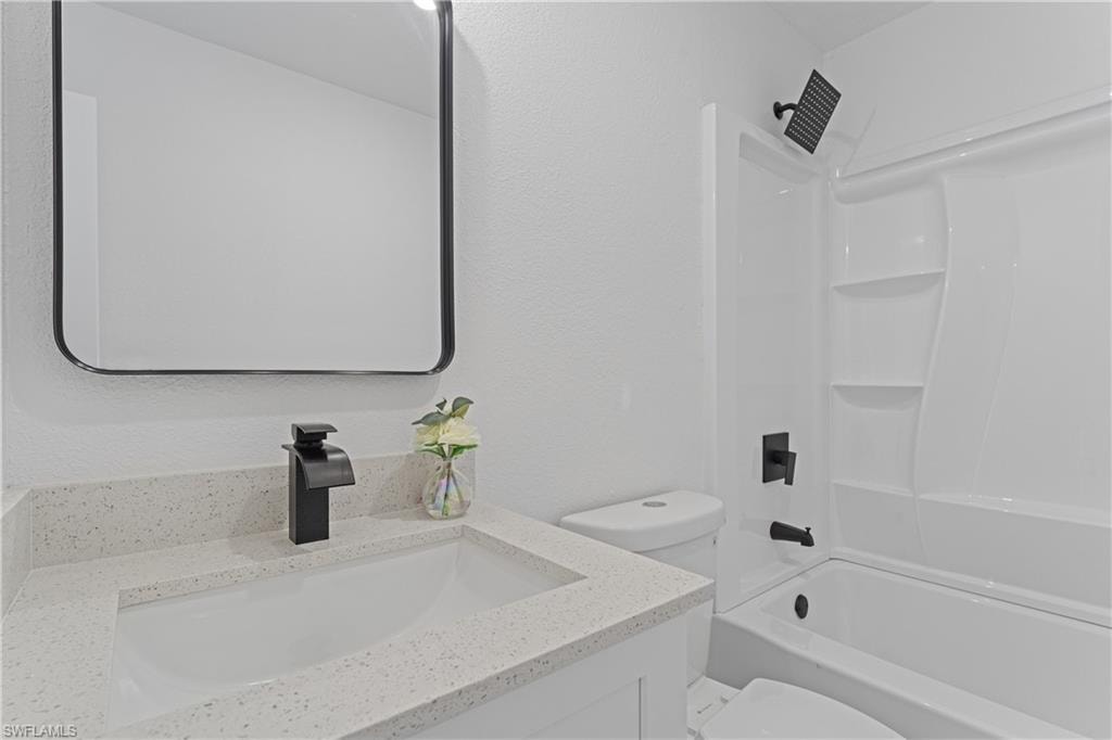 Bathroom with a white vanity featuring a speckled countertop, integrated sink, and black modern faucet
