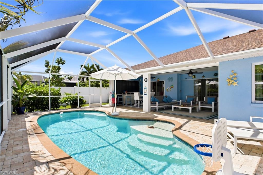 Screened-in outdoor living space, swimming pool with integrated steps, a covered patio, and gorgeous paver decking.
