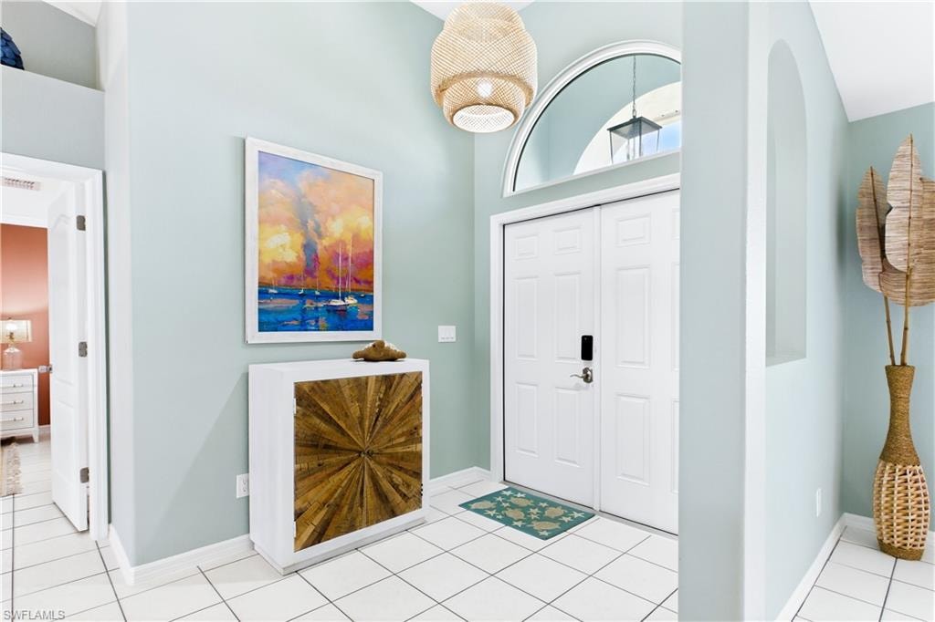Arched transom window, double entry doors, high ceilings, tiled flooring, and an arched wall niche.