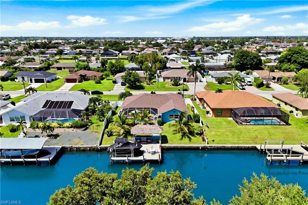 Waterfront property featuring a private boat dock, screened-in swimming pool, and a well-maintained lawn.
