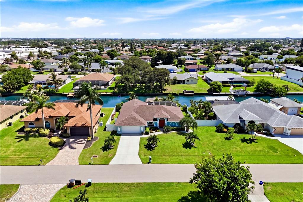 Gulf Access canal home with mature palm trees, a well-maintained lawn.