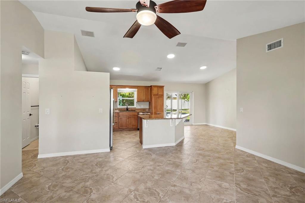 Vaulted ceiling with a ceiling fan, recessed lighting, and tile flooring throughout