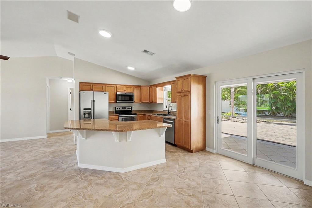 Kitchen featuring wood cabinetry, stainless steel appliances, a multi-level island with a countertop, and tile flooring