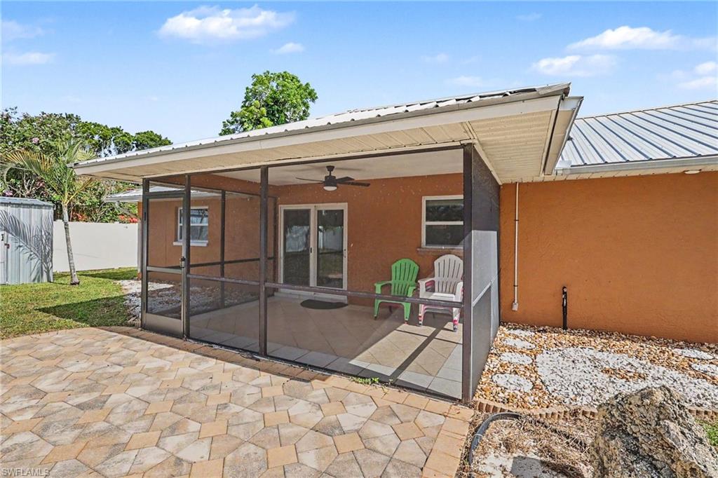 Screened patio with a ceiling fan, sliding glass doors, exterior metal roof, and an adjacent paver patio
