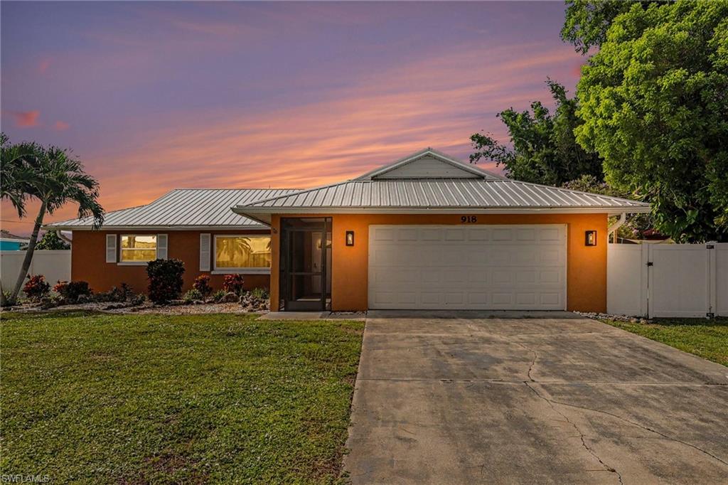 Exterior featuring a metal roof, attached garage, screened entry, and a privacy fence