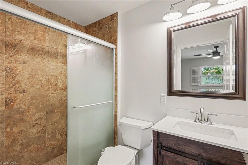 Shower with sliding glass enclosure, stone-look tile surround, and tile flooring