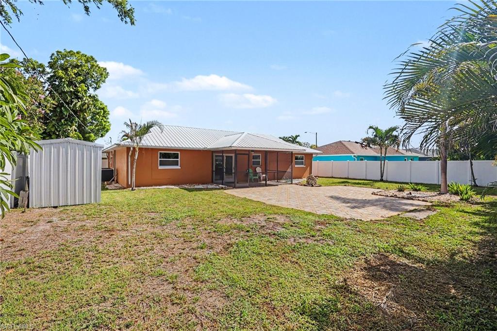 Expansive backyard featuring a paver patio, screened lanai, mature palm trees, and privacy fencing