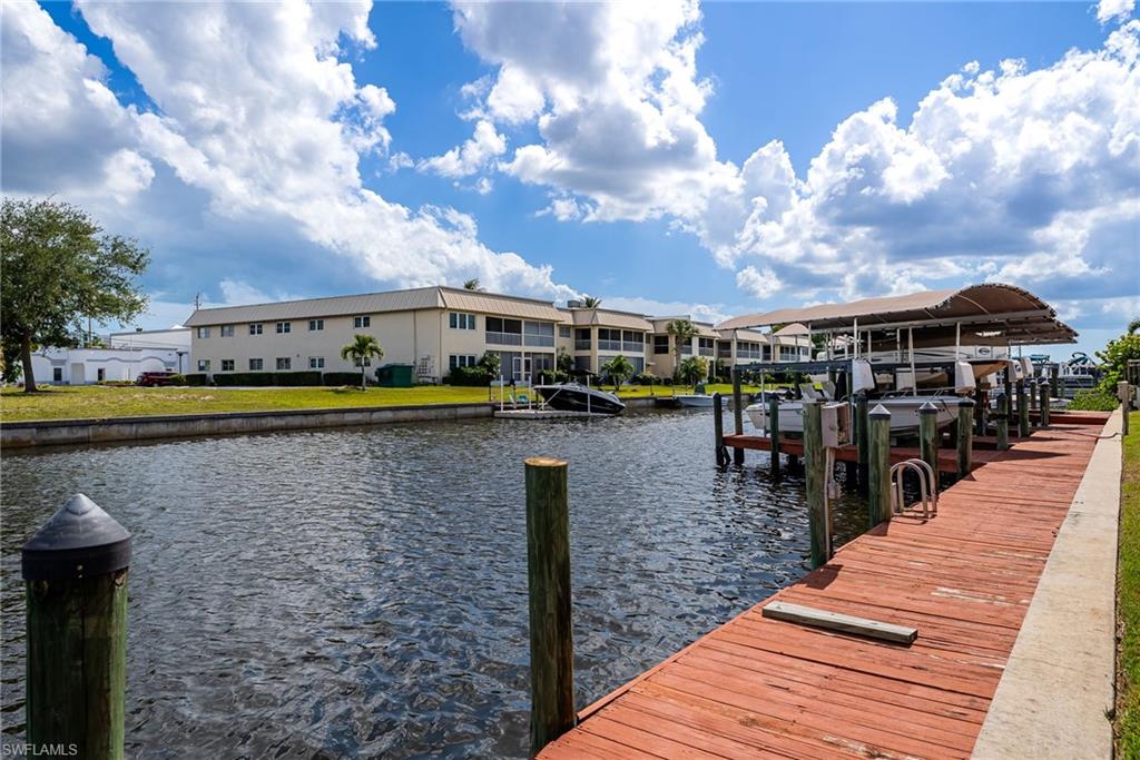 Waterfront property featuring a wooden dock, boat lifts, and covered boat storage