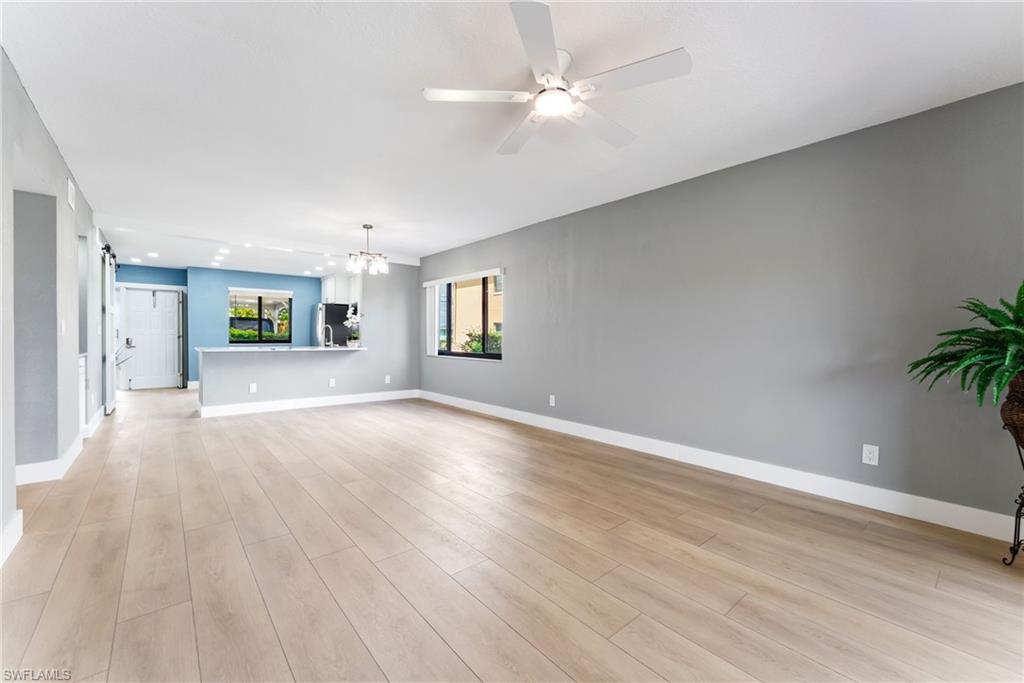 Light wood-finish flooring, recessed lighting, ceiling fan, and modern pendant light fixture
