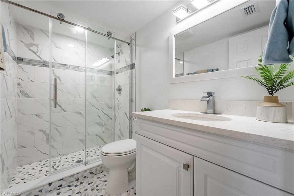 Glass-enclosed shower with subway tile surround, mosaic shower floor, and sliding door