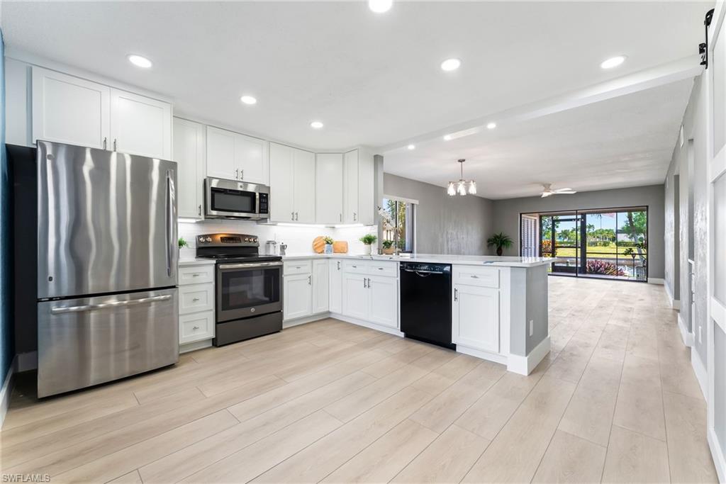 Kitchen featuring white cabinetry, stainless steel appliances, an island with a built-in dishwasher, and wood-finish flooring