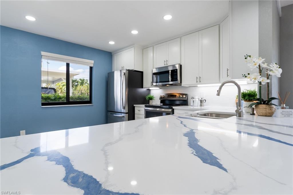Kitchen featuring white cabinetry, a large window, stainless steel appliances, recessed lighting, and a countertop with blue veining