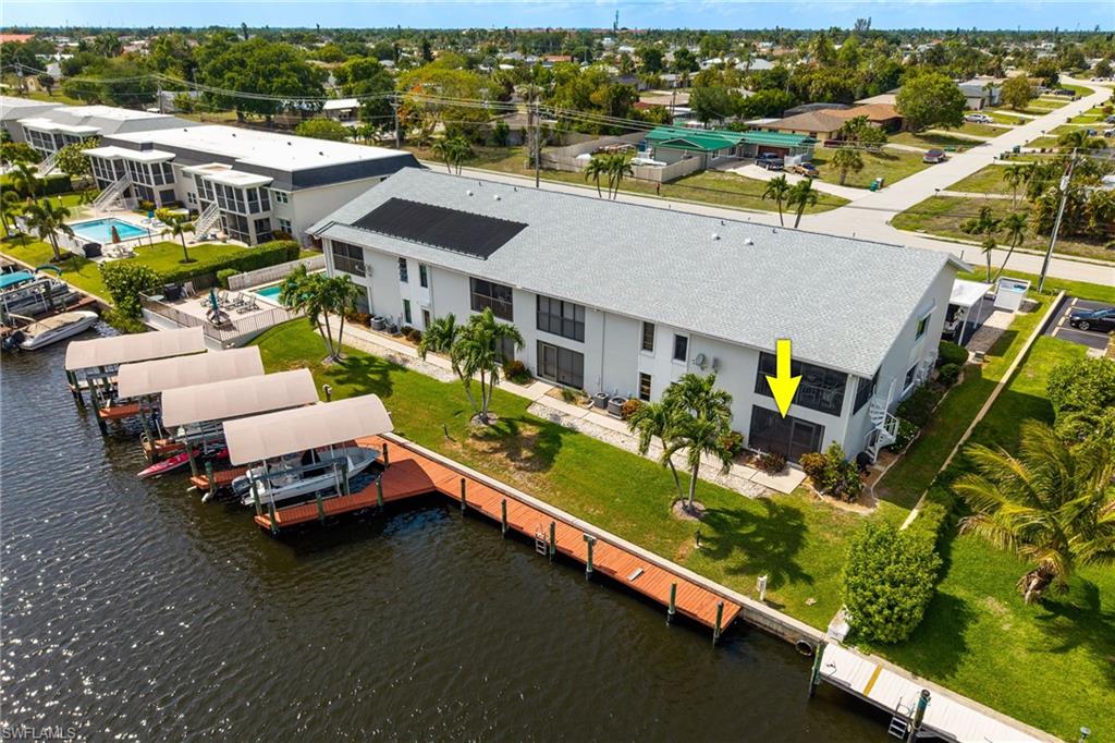 Waterfront property featuring a private boat dock, covered boat slips, direct water access, and mature landscaping