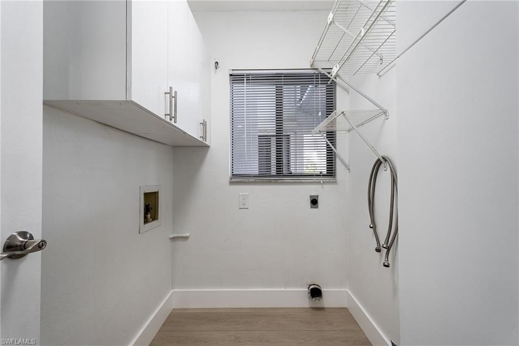 Laundry area with wood-finish flooring, white cabinetry, a window with blinds, and built-in wire shelving