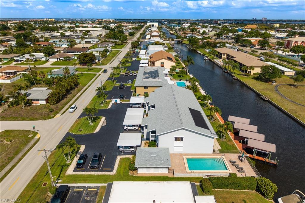 Outdoor swimming pool with surrounding patio, canal frontage with boat docks, and covered parking spaces