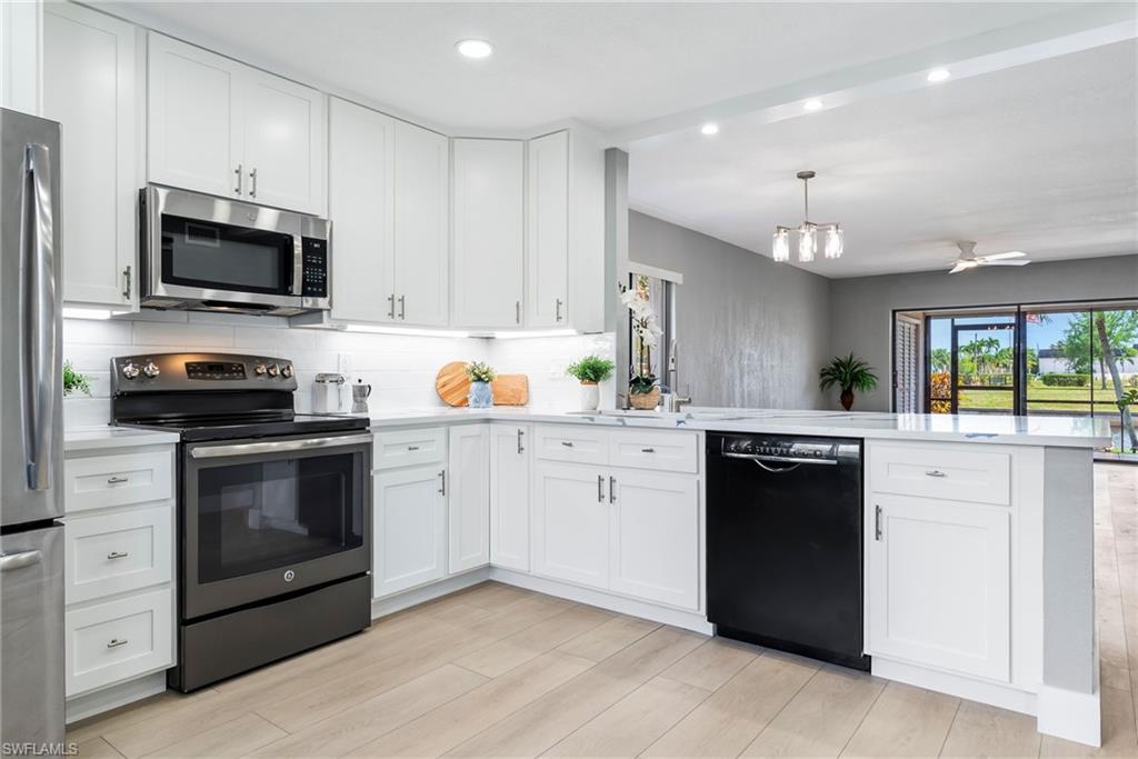Modern kitchen featuring white cabinetry, stainless steel appliances, light-toned wood-finish flooring, and white countertops