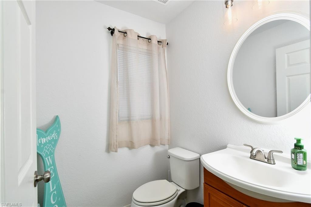 Modern vanity with integrated sink, brushed nickel faucet, large circular mirror, and built-in lighting