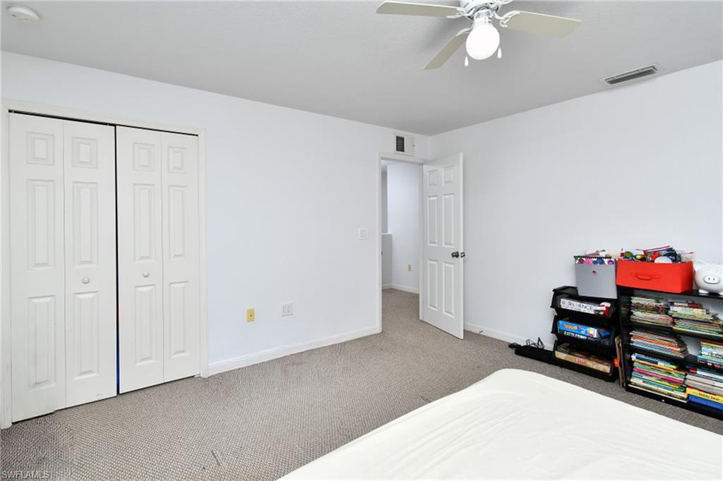 Neutral-toned carpet flooring, white walls, ceiling fan with integrated lighting, and a white paneled door