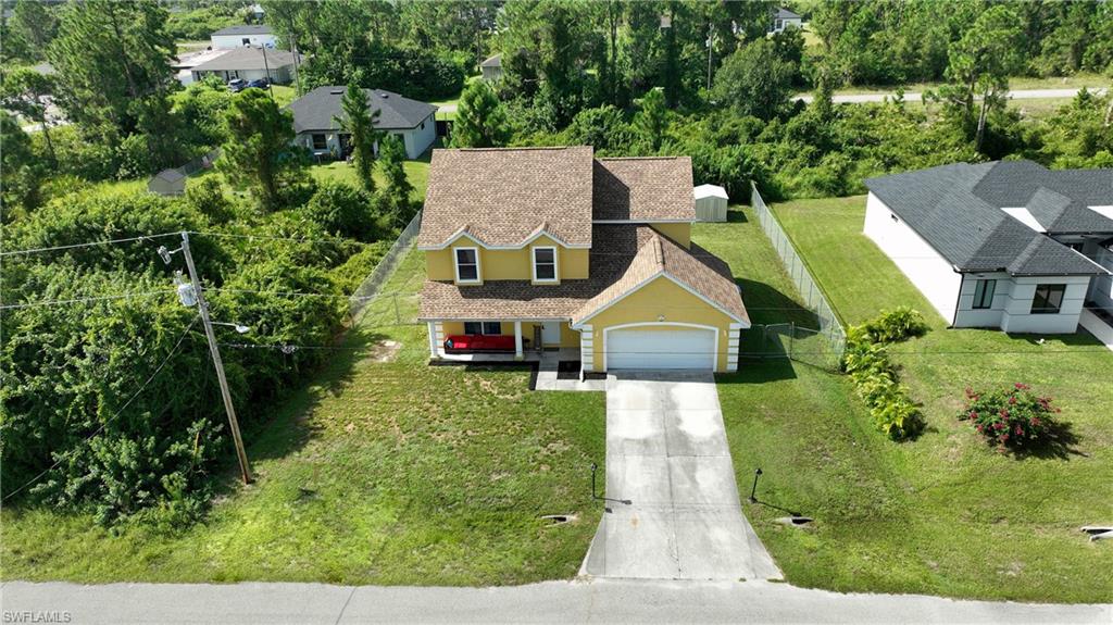 Yellow exterior with a two-story design, attached garage, and concrete driveway