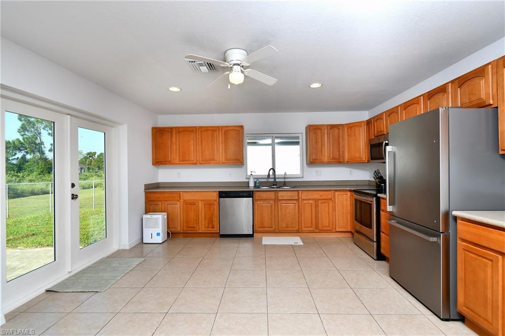 Kitchen featuring tile flooring, wood-finish cabinetry, stainless steel appliances, recessed lighting, and a ceiling fan