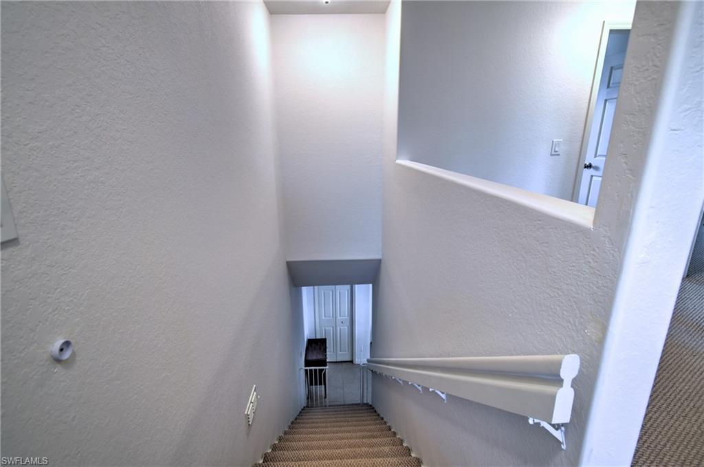 Carpeted staircase with a partial wall railing and a wall-mounted handrail