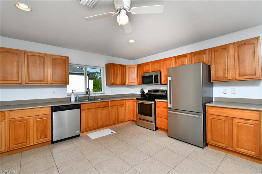 Kitchen featuring wood cabinetry, stainless steel appliances, a ceiling fan, and recessed lighting