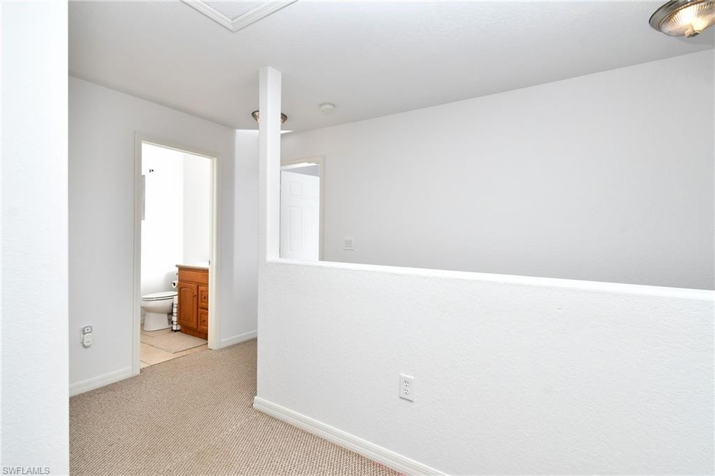 Carpeted floor, white painted walls, recessed lighting, half-wall partition, and wood-finish vanity
