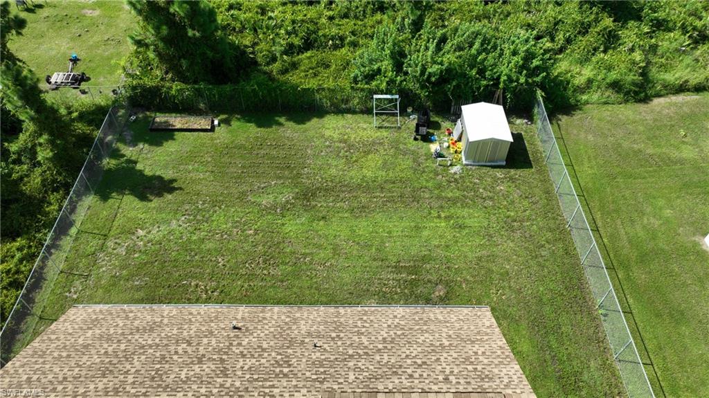Expansive fenced yard featuring a storage shed and natural landscaping