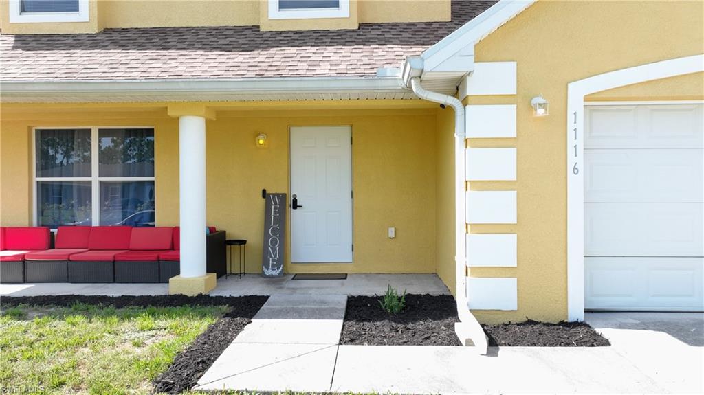 Stucco exterior with decorative trim, covered entry, and single-panel garage door