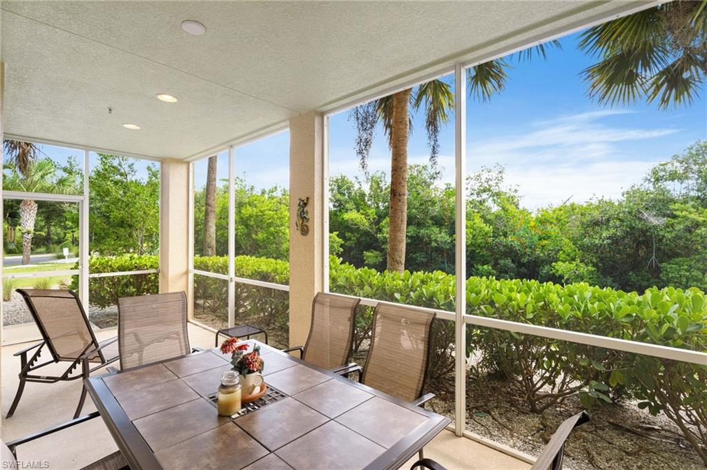 Screened patio featuring a tile dining table, recessed lighting, and lush perimeter landscaping