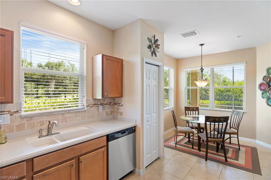 Kitchen area featuring a double basin sink, integrated dishwasher, and wood-finish cabinetry