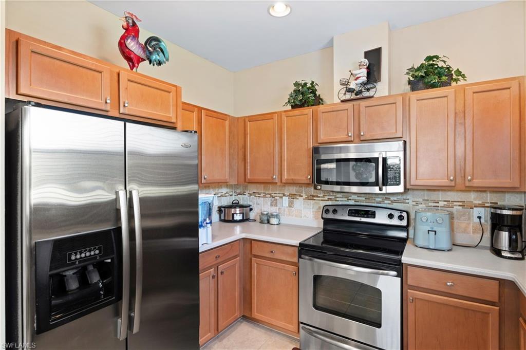 Kitchen featuring stainless steel appliances, wood-finish cabinetry, and solid surface countertops