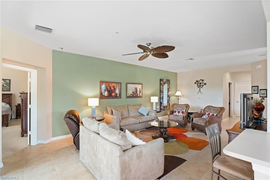 Recessed lighting, ceiling fan with natural wood-finish blades, tiled flooring, open doorway