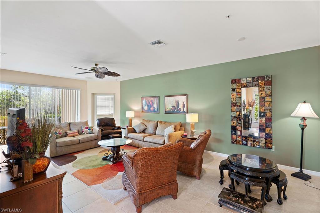Spacious living area featuring tile flooring, a ceiling fan, and sliding glass doors with vertical blinds