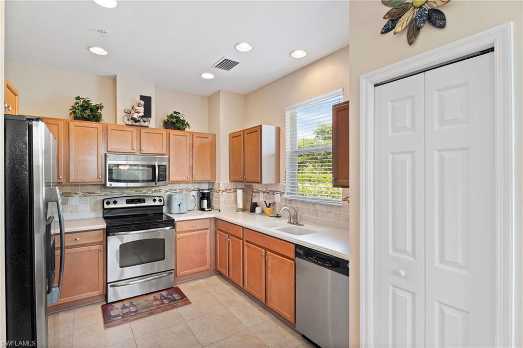 Kitchen featuring stainless steel appliances, wood-finish cabinetry, tile flooring, and recessed lighting
