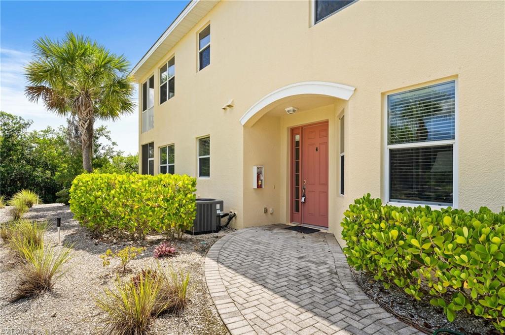 Stucco exterior with multiple windows, arched entryway, and a paver walkway