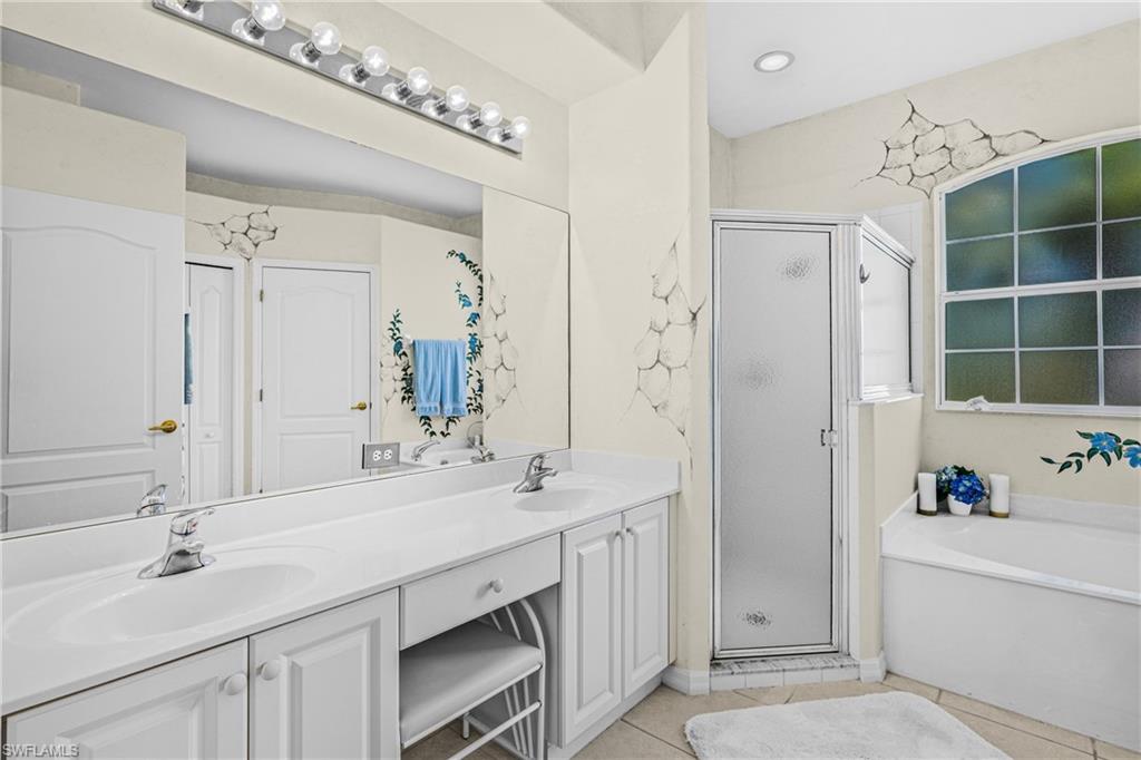 Dual vanity with integrated sinks, large mirror, walk-in shower with frosted glass, and a built-in soaking tub