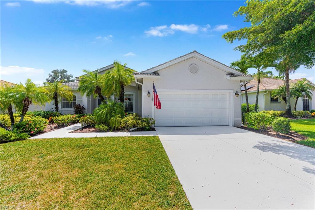 White stucco exterior with a tiled roof, attached garage, and a concrete driveway