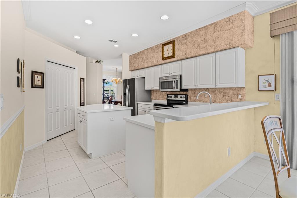 Kitchen featuring white cabinetry, stainless steel appliances, a breakfast bar, recessed lighting, and tile flooring