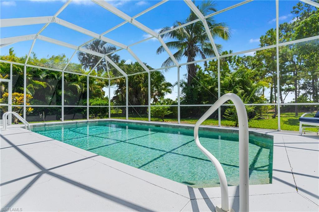 Screened enclosure featuring a rectangular pool, concrete decking, and integrated pool handrail